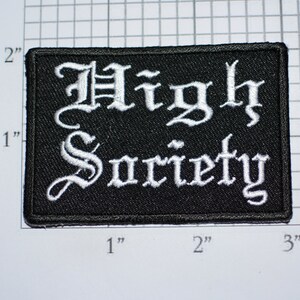 May include: Black embroidered patch with white lettering that reads "High Society" in a gothic font.