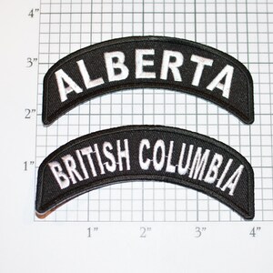 May include: Two black fabric patches with white embroidered text. The top patch reads "ALBERTA" and the bottom patch reads "BRITISH COLUMBIA".