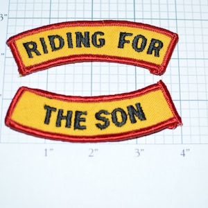 May include: Two yellow and red embroidered patches with black text. The top patch reads "RIDING FOR" and the bottom patch reads "THE SON".