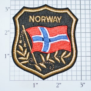 May include: A black and gold embroidered patch with the word "NORWAY" and a red, white, and blue flag with a gold leaf design. The patch is approximately 3 inches tall.