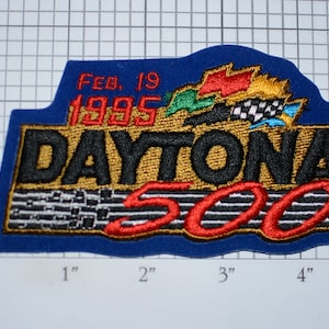 May include: A blue embroidered patch with the text "DAYTONA 500" in gold and black lettering. The text "Feb. 19 1995" is in red lettering above the main text. The patch features a checkered flag and other racing flags.