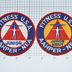 May include: Two round embroidered patches with the text "Fitness U.S.A. AAHPER-NEA" in blue and red. One patch says "Junior" and the other says "Junior Merit".
