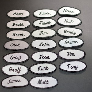 May include: Twenty white oval-shaped patches with black embroidered names, including Adam, Jason, Neiko, Brett, Jesse, Nick, Brent, Jim, Randy, Chad, John, Steve, Gary, Josh, Tim, Geoff, Kurt, Tony, James, and Matt.