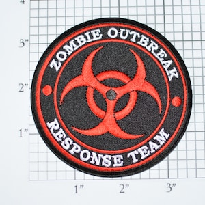 May include: A black and red embroidered patch with a biohazard symbol and the text "Zombie Outbreak Response Team".
