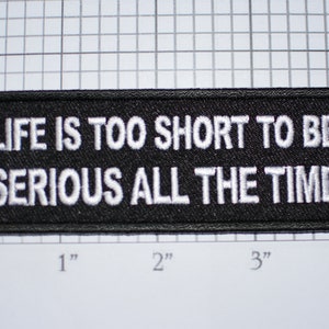 May include: Black embroidered patch with white text that reads "Life is too short to be serious all the time".