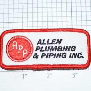May include: Red and white embroidered patch with the text "ALLEN PLUMBING & PIPING INC." and a red circle with the letters "APP" in white.