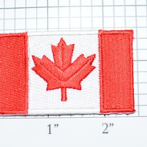May include: A red and white Canadian flag patch with a red maple leaf in the center. The patch is approximately 2 inches wide and 1 inch tall.