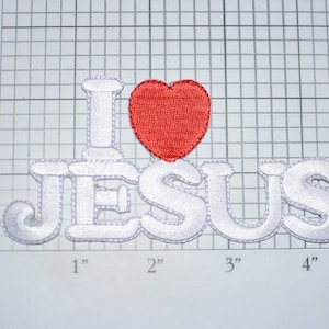 May include: White felt applique patch with the words "I love Jesus" in a white, puffy font. A red felt heart is between the "I" and the "J".