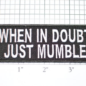 May include: Black embroidered patch with white text that reads "WHEN IN DOUBT JUST MUMBLE".