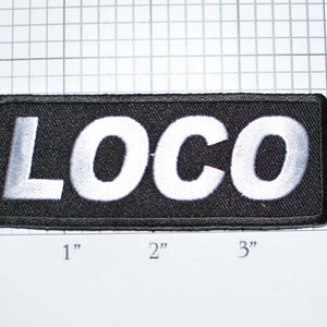 May include: Black fabric patch with white embroidered text that reads "LOCO".