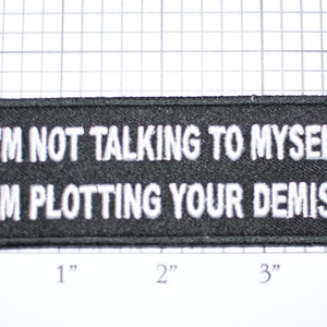 May include: Black embroidered patch with white text that reads "I'm not talking to myself I'm plotting your demise".