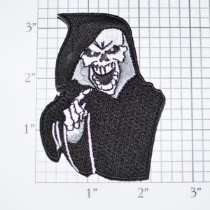 May include: Black and white embroidered iron-on patch of the Grim Reaper pointing a finger. The Grim Reaper is wearing a black hooded robe and has a skull face with a menacing grin.