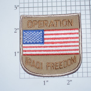 May include: A tan embroidered patch with the text "OPERATION IRAQI FREEDOM" and an American flag in the center.