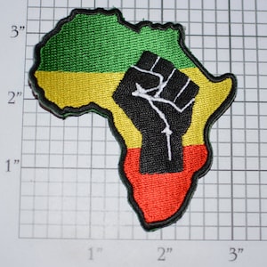 May include: A green, yellow, and red embroidered patch shaped like the continent of Africa with a black fist raised in the center.