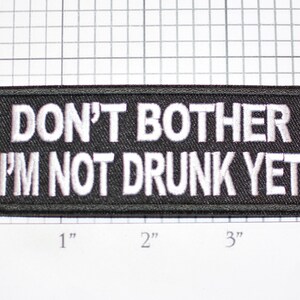 May include: Black embroidered patch with white text that reads "DON'T BOTHER I'M NOT DRUNK YET".