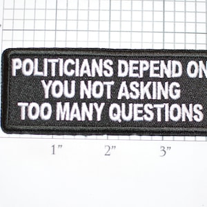 May include: Black embroidered patch with white text that reads "Politicians depend on you not asking too many questions".