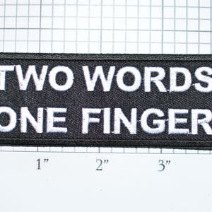 May include: Black embroidered patch with white text that reads "TWO WORDS ONE FINGER".