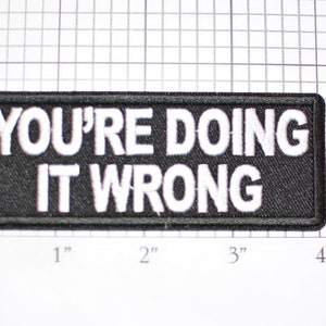 May include: Black rectangular patch with white embroidered text that reads "YOU'RE DOING IT WRONG". The patch measures approximately 4 inches long and 1 inch high.