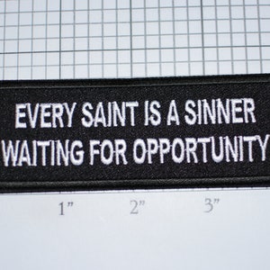 May include: Black embroidered patch with white text that reads "Every Saint Is A Sinner Waiting For Opportunity".