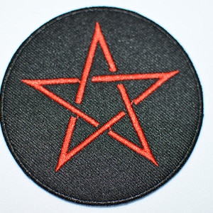 May include: A black and red embroidered patch with a five-pointed star in the center. The star is outlined in red and has a red line running through the center.