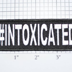 May include: Black embroidered patch with white text that reads "#INTOXICATED". The patch is approximately 3 inches wide and 1 inch tall.