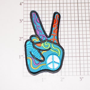 May include: A blue peace sign patch with colorful swirls and a white peace symbol in the center. The patch is outlined in black.