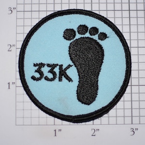 May include: A light blue round patch with a black footprint and the text "33K" in black.