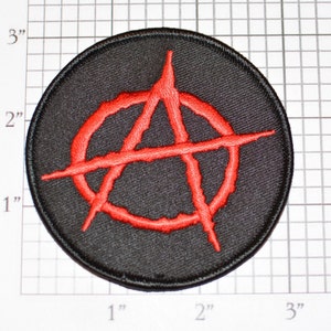 May include: Round black patch with a red anarchy symbol embroidered in the center. The patch is approximately 3 inches in diameter. The red symbol is a stylized letter "A" inside a circle.