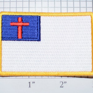 May include: A white patch with a blue and red cross in the upper left corner. The patch has a yellow border and measures approximately 2 inches by 3 inches.
