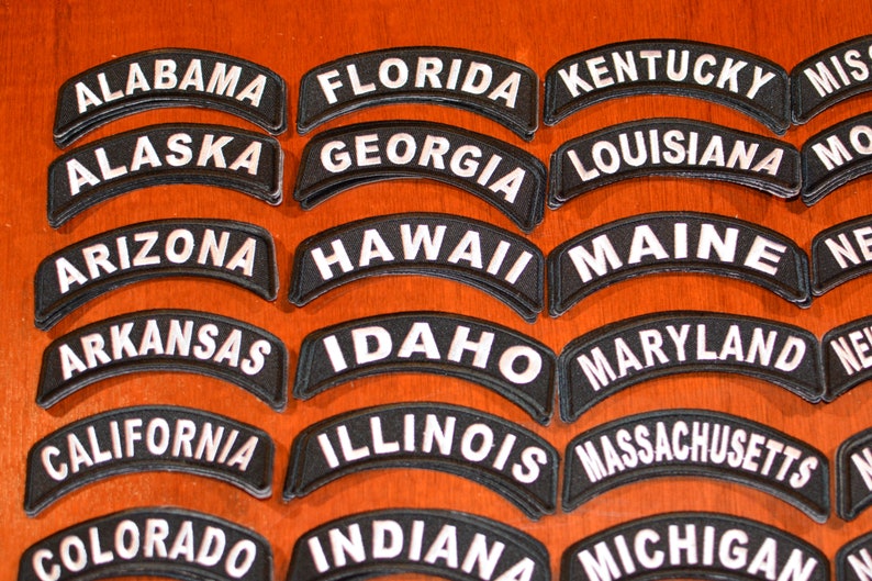 Puede incluir: Un conjunto de parches bordados negros en forma de arco, cada uno con el nombre de un estado estadounidense en letras blancas. Incluyen: Pennsylvania, Rhode Island, South Carolina, South Dakota, Tennessee y Texas.