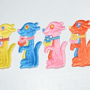 May include: Four embroidered iron-on patches of cartoon animals holding flowers. The animals are yellow, blue, pink, and orange. Each animal has a flower in its paw and a collar around its neck.
