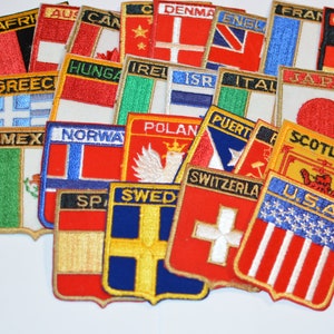 May include: A collection of embroidered fabric patches featuring flags from various countries, including the United States, Canada, Mexico, Germany, Japan, and many more. The patches are in various colors and designs, with some featuring the country's name.