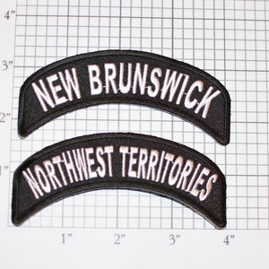 May include: Two black embroidered patches with white lettering. The top patch reads "NEW BRUNSWICK" and the bottom patch reads "NORTHWEST TERRITORIES".
