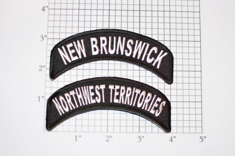 May include: Two black embroidered patches with white lettering. The top patch reads "NEW BRUNSWICK" and the bottom patch reads "NORTHWEST TERRITORIES".