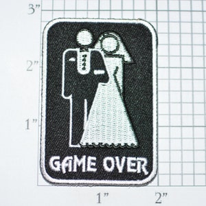 May include: Black and white embroidered patch with a bride and groom in a wedding pose. The patch is 2 inches by 3 inches and has the text "GAME OVER" in white lettering.