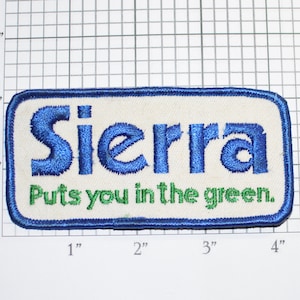 May include: Embroidered patch with the word "Sierra" in blue, above the phrase "Puts you in the green." The patch is rectangular, with a white background and a blue border. The patch measures approximately 3 inches by 2 inches.