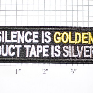 May include: Black embroidered patch with white text that reads "Silence is Golden Duct Tape is Silver". The word "Golden" is embroidered in yellow.