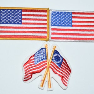 May include: Three embroidered American flag patches. Two are rectangular and one is a pair of crossed flags with a white background.