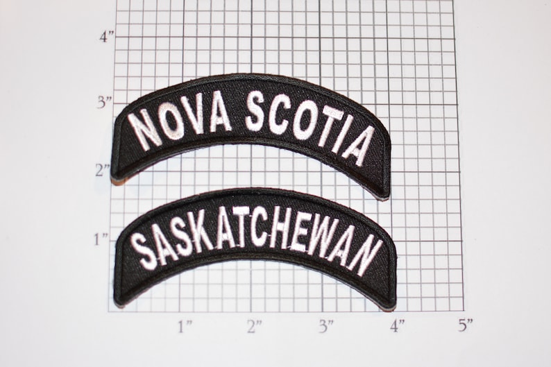 May include: Two black embroidered patches with white lettering. The top patch reads "NOVA SCOTIA" and the bottom patch reads "SASKATCHEWAN".