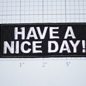 May include: Black embroidered patch with white text that reads "HAVE A NICE DAY!"