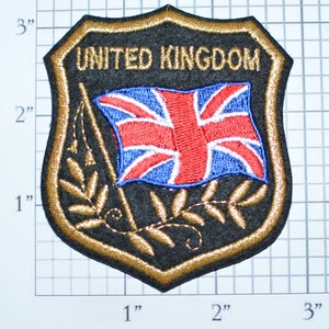 May include: A gold embroidered patch with a black background featuring the Union Jack flag and the text "UNITED KINGDOM".