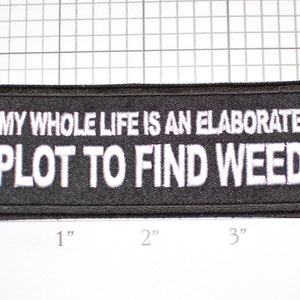 May include: Black embroidered patch with white text that reads "My whole life is an elaborate plot to find weed".