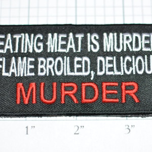 May include: Black embroidered patch with white text that reads "Eating meat is murder, flame broiled, delicious" and red text that reads "murder".