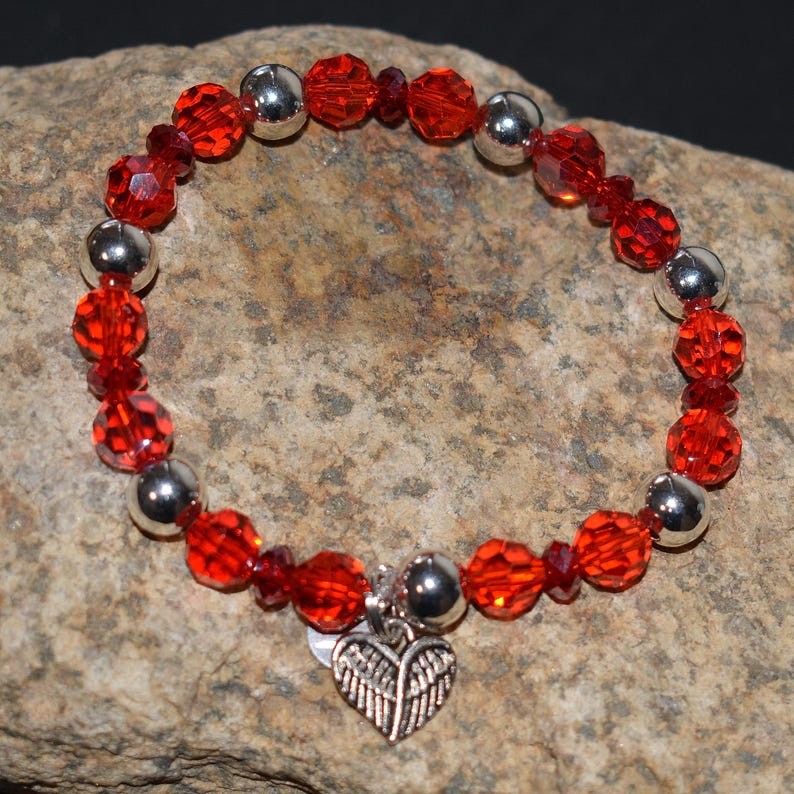 Puede incluir: Una pulsera roja con cuentas rojas y plateadas y un dije de coraz&oacute;n. La pulsera presenta cuentas rojas facetadas y cuentas plateadas redondas. El dije de coraz&oacute;n tiene un dise&ntilde;o de alas.