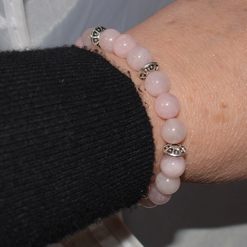 Op de afbeelding: Een armband van roze edelstenen met zilveren accenten. De armband is gemaakt van ronde kralen en heeft een eenvoudig ontwerp.