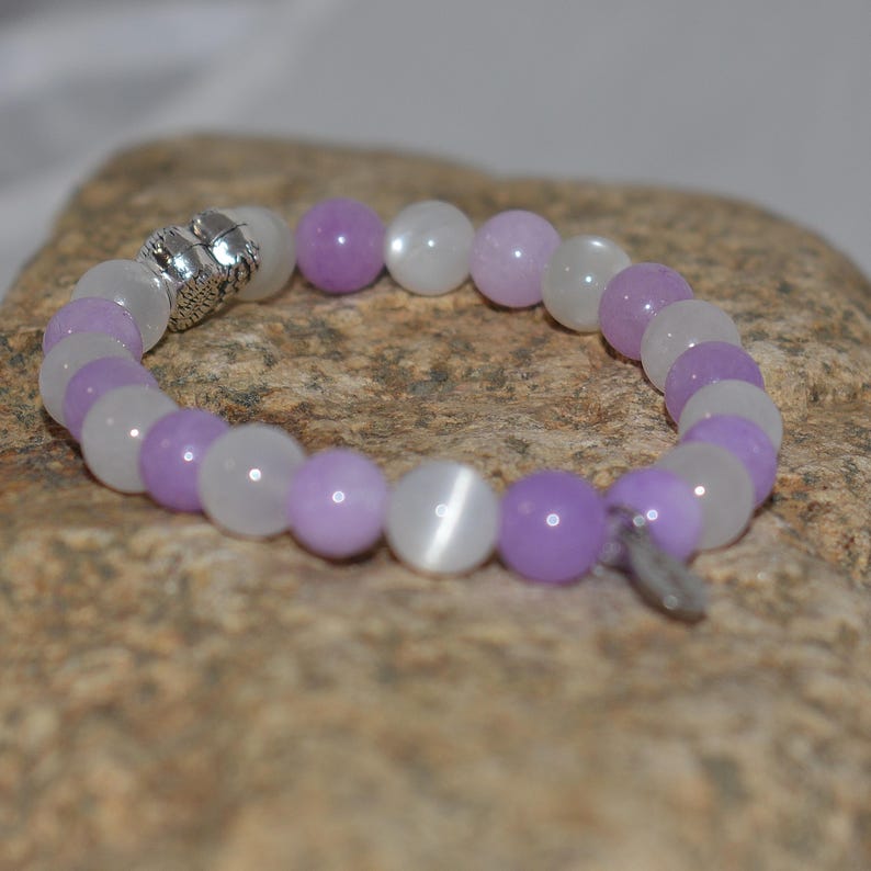 May include: A purple and white beaded bracelet with a silver clasp. The beads are round and have a smooth, polished finish.