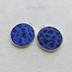 May include: Two gold-toned round pendants with a blue and black leopard print design.