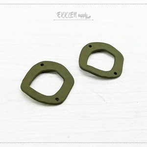 May include: Two olive green, abstract-shaped jewelry components with three small holes each. The components have a matte finish and a unique, organic design. The image includes the text "EKKLEN supply" in the upper right corner.
