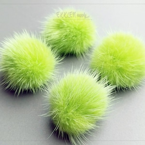 May include: Four lime green faux fur pom poms. The pom poms are soft and fluffy.