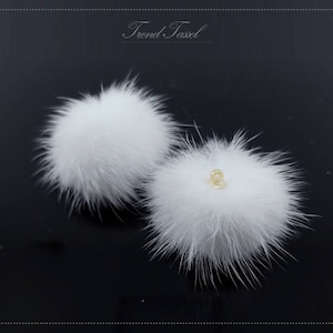 May include: Two white fluffy pom poms with a gold bead accent. The pom poms are soft and fluffy and would be perfect for adding a touch of whimsy to any project.